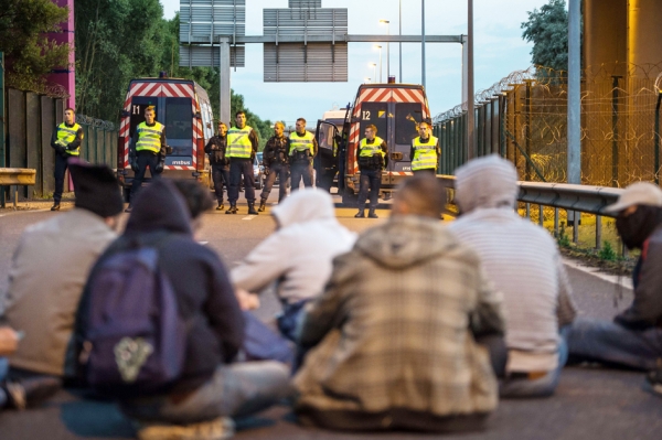 一群难民正在与阻挡他们的宪兵对峙。每天晚上,总会有数以百计的难民做出危险的尝试。(AFP/Getty Images) 一群难民正在与阻挡他们的宪兵对峙。每天晚上,总会有数以百计的难民做出危险的尝试。(AFP/Getty Images)