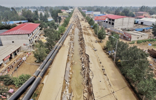 多名村民证实,七里河河道变窄的一个重要的原因是,大贤桥附近铺设热力管道,这项工程挖出来的渣土堵塞了部分河道,造成大贤桥下的部分涵洞没法完全发挥排水功能。上图为洪水将坑内的管道冲到路边。(AFP/Getty Images) 多名村民证实,七里河河道变窄的一个重要的原因是,大贤桥附近铺设热力管道,这项工程挖出来的渣土堵塞了部分河道,造成大贤桥下的部分涵洞没法完全发挥排水功能。上图为洪