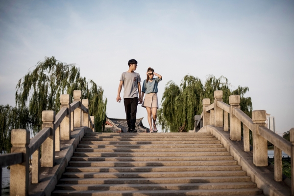 现在越来越多的婚姻强调金钱，强调门当户对的条件。中国人重家庭重伦理的理念越来越被淡忘。图为一对情侣走在济南大明湖的一座桥上。（Getty Images）