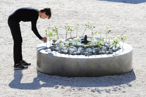 10月15日,一位青年将一朵代表尼斯恐袭遇难者的白玫瑰插在花坛里。 (AFP/Getty Images) 10月15日,一位青年将一朵代表尼斯恐袭遇难者的白玫瑰插在花坛里。 (AFP/Getty Images)