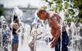 在极端高温天气下，一名男子在喷水池喷水降温。（ALEXANDER NEMENOV/AFP/Getty Images）