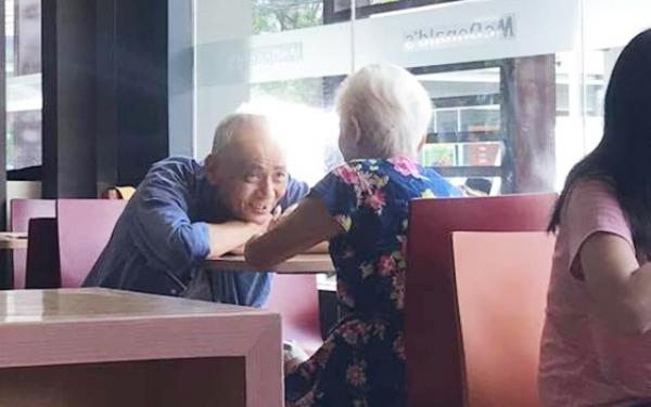 一对满头白发的夫妇在麦当劳面对面地坐着。