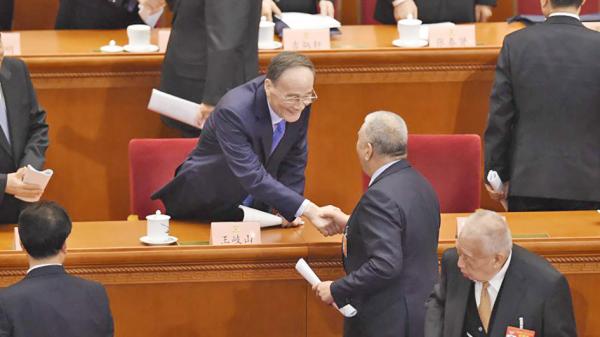 2019年3月两会期间,王岐山和与会者握手,右下握手者为前香港特首董建华。(AFP/Getty Images )