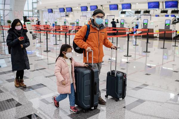 图为1月22日,戴着口罩的一家三口在北京机场。(AFP via Getty Images)