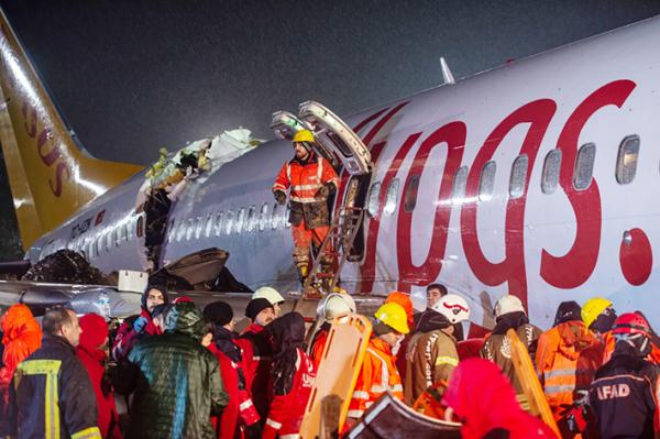 2月5日,土耳其飞机降落冲出跑道,救援人员和消防队员在抢救伤者。(Getty Images)