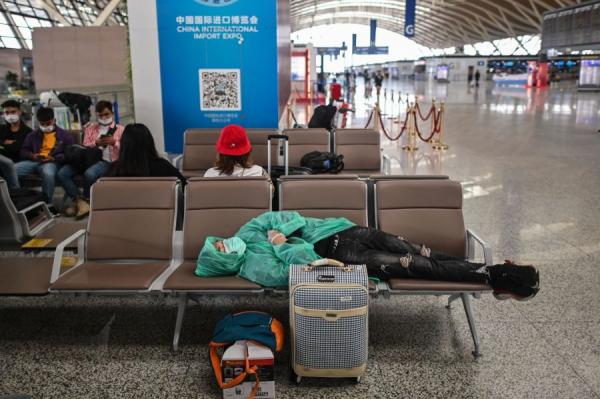 澳洲华女回国刚下机就晕倒,倒地20分钟送医猝死。图为3月26日,一名身穿保护衣的乘客躺在候机室的椅子上。(非本文当事人图片/图片来源:HECTOR RETAMAL/AFP via Getty Images)