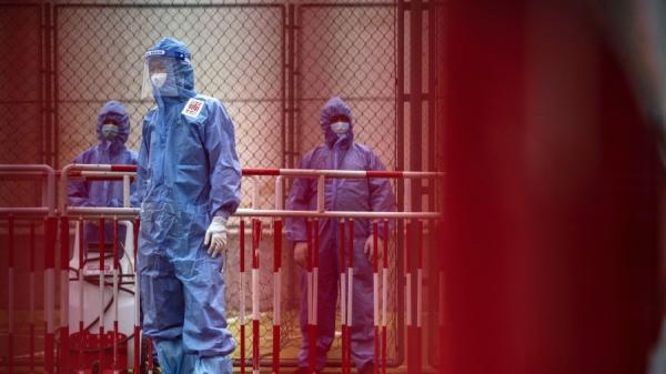2020年6月24日,防疫人员穿着防护服在西城区的一个政府测试地点观看人们接受病毒测试。(图片来源:Kevin Frayer/Getty Images)