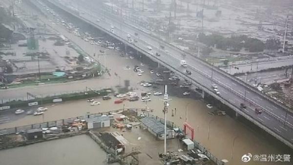 当地街道积水严重,不少汽车被泡在水中,人们蹚水行走。(图片来源:网络图片)