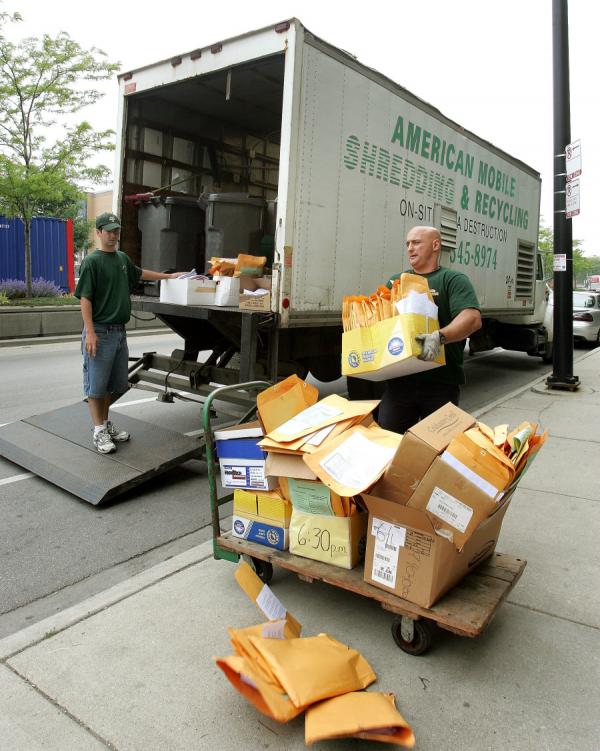 图为两名碎纸公司的工人将文件搬上碎纸大卡车，准备销毁文件。（示意图/图片来源：Tim Boyle/Getty Images）