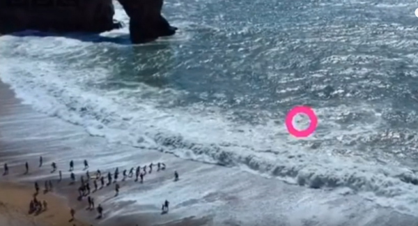 一男子向正在沙滩上晒太阳的游客求救。(图片来源:视频截图)