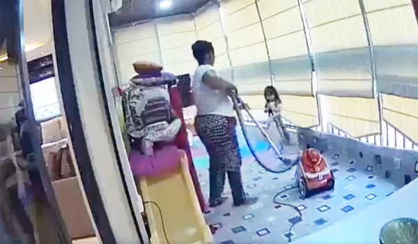 8月4日,黎巴嫩大爆炸前一名非裔女佣正在阳台用吸尘器打扫,一名小女童坐在角落玩耍。(Getty Images)