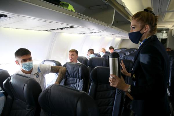 一名手拿热水瓶的空姐在与乘客交谈(图片来源:Giampiero Sposito/Getty Images)