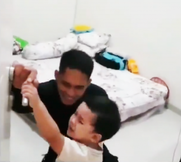 伊曼2岁的儿子大声哭闹,拼命用小手阻挡父亲出门。(视频截图)