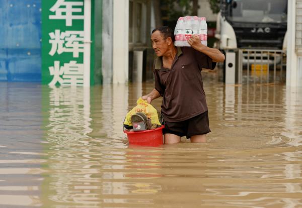7月23日,郑州市一名男子穿过被洪水淹没的街道。(NOEL CELIS/AFP via Getty Images)