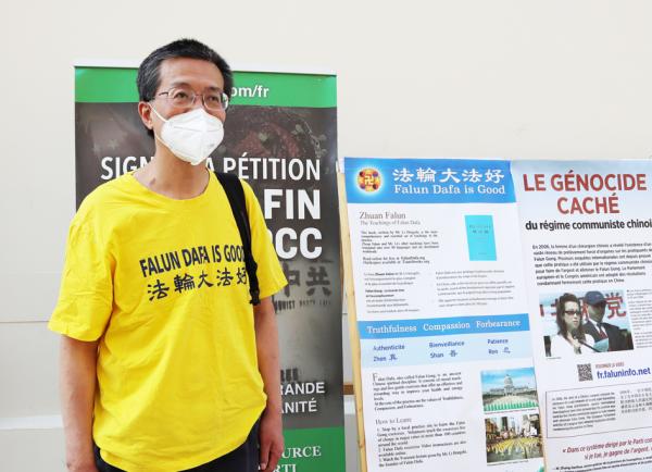 李旭彤博士摄于7月17日法轮功反迫害集会的展板前。