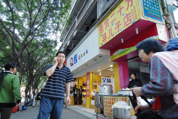 孩子被拐后,孙海洋(持手机者)将自己的包子铺改成了寻子店,并贴出悬赏小广告,悬赏20万寻找儿子的下落。他的故事后来被改编成了电影《亲爱的》,此图摄于2008年11月。(WANG LEI/AFP via Getty Images)