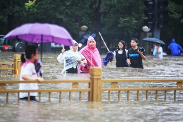 人们涉水走过街道。(STR/AFP/Getty Images)