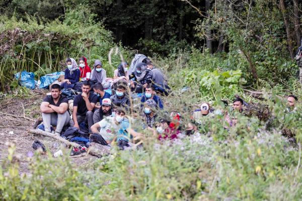 2021年8月20日,来自阿富汗的难民坐在波兰东北部比亚韦斯托克附近小村庄的地上,该村庄靠近白罗斯边境。(WOJTEK RADWANSKI/AFP/Getty Images)