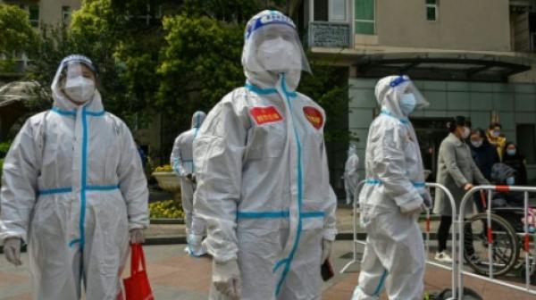 上海静安区防疫人员和志愿者在一个大院里观看居民接受核酸检测。(图片来源:HECTOR RETAMAL/AFP via Getty Images)