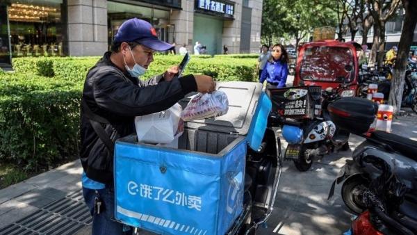 外卖人员在北京一条街道上检查食品订单,示意图。(图片来源:JADE GAO/AFP via Getty Images)