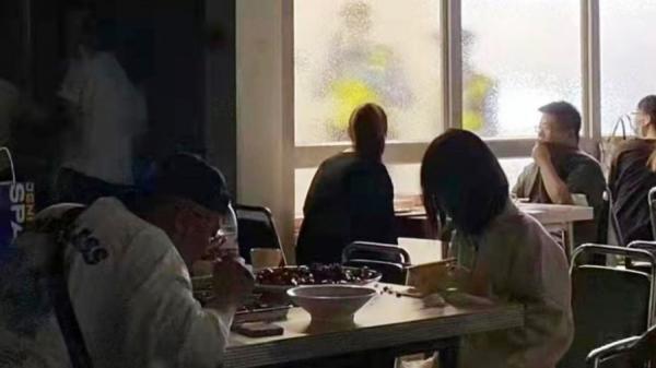 上海多名男女在一家快餐店进餐,现场光线极弱,透过玻璃可见窗外两名警察正在巡查,食客们凝视外面2名警察。(图片来源:网络图片)