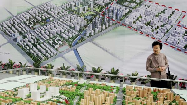 资料照。一位中国妇女在房地产交易会上观看公寓楼模型。(Getty Images)