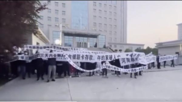 河南村镇银行储户14日在河南焦作人民银行楼前聚集抗议。(图片来源:视频截图)