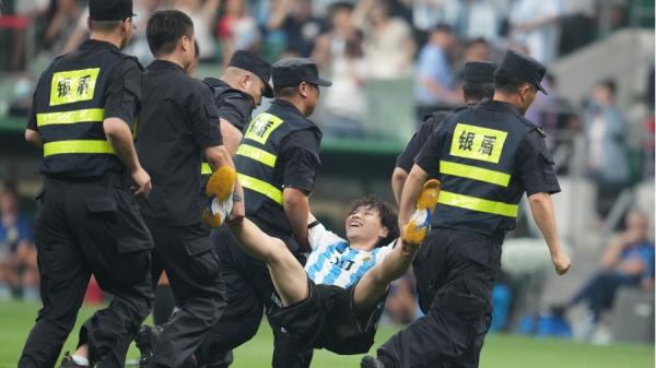 15日晚中国球迷被保安按在草地上,不过,他面带微笑被抬下赛场。(图片来源:Fred Lee/Getty Images)