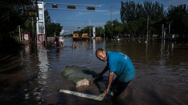 8月5日河北涿州一男子在洪水退去后的淤泥中拉着打捞的物品。(图片来源:Getty Images)