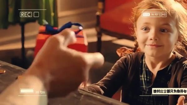 女孩笑逐颜开,伸出双手正要接过老人为她包装好、里头装有绿松石项链的礼品 盒。(图片来源:视频截图)