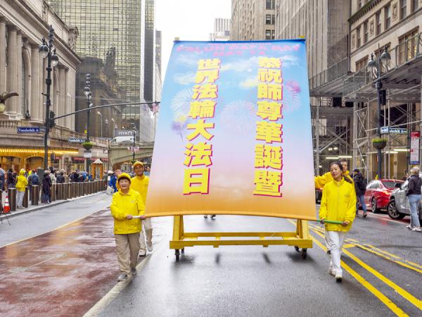 参加游行的法轮功学员推着载有条幅 “ 恭祝师尊华诞暨世界法轮大法日 ” 的车。(摄 影:Leo/看中国)