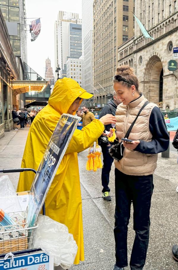 游行时,法轮功学员在路边给行人送真相资料和小莲花。(摄影: Wei J C)