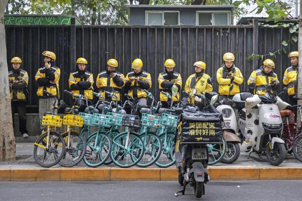 2024年10月30日,北京美团外卖员在上班前排队聆听主管指示。(Kevin Frayer/Getty Images)