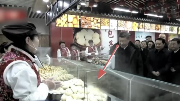 习近平在看包子,他身后还有写着“包子”二字的招牌。(图片来源:视频截图)