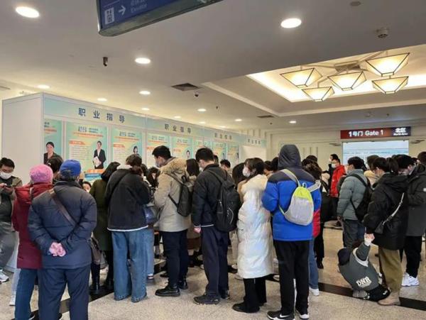 求职者在上海一个就业指导站台前咨询,并在工作人员的指导下修改简历。