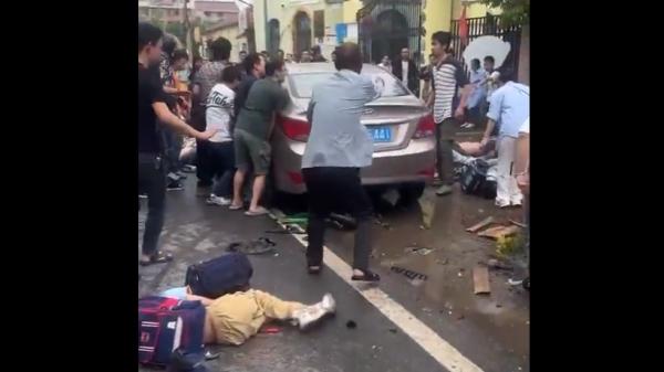 浙江金华苏孟小学门口放学时一辆轿车疯狂冲撞学生人群,有学生被压在车底。(图片来源:视频截图)