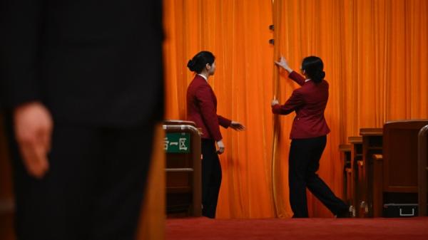 2024年3月5日,在北京人民大会堂举行的全国人民代表大会开幕典礼上,工作人员在拉上大厅入口处的帷幕。(图片来源:Getty Images)