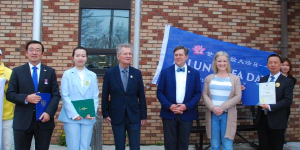 2025年5月2日,加拿大安省布灵顿(Brington)市政府前,市长布莱恩.奥斯特兰德(Brian Ostrander)(右三)和副市长当.安德森(Don Anderson)(左三)以及市议员怀特(Bobbi Wright)(左二)主持法轮大法旗升旗仪式,庆祝世界法轮大法日33周年。图为市长(右三)与部分法轮功学员合影(图片来源:EpochTimes)