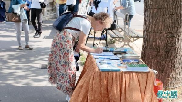 在解体中共请愿书上签字的法国民众。(法国看中国记者站)