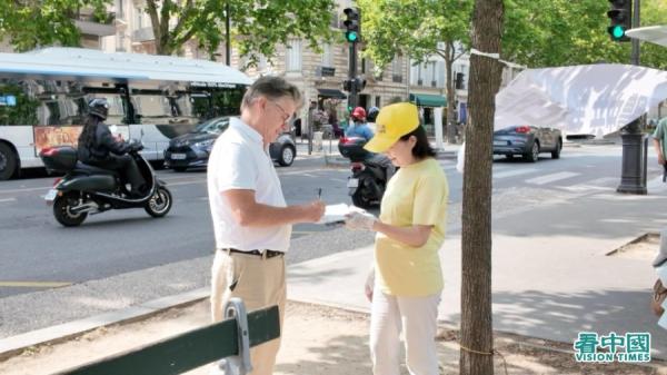 在解体中共请愿书上签字的法国民众。(法国看中国记者站)