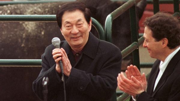 1999年4月11日，中共国务院总理朱镕基（左）在伊利诺伊州利伯蒂维尔的马雷尔巴农场向农民发表讲话时与汤姆·普利兹克一起鼓掌。（图片来源：TANNEN MAURY/AFP via Getty Images）