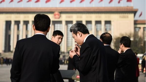 2018年3月19日,在北京人民大会堂举行的第十三届全国人民代表大会第七次全体会议召开前,与会代表们在天安门广场吸烟。(图片来源:Etienne Oliveau/Getty Images)