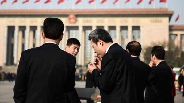 2018年3月19日，在北京人民大会堂举行的第十三届全国人民代表大会第七次全体会议召开前，与会代表们在天安门广场吸烟。（图片来源：Etienne Oliveau/Getty Images）