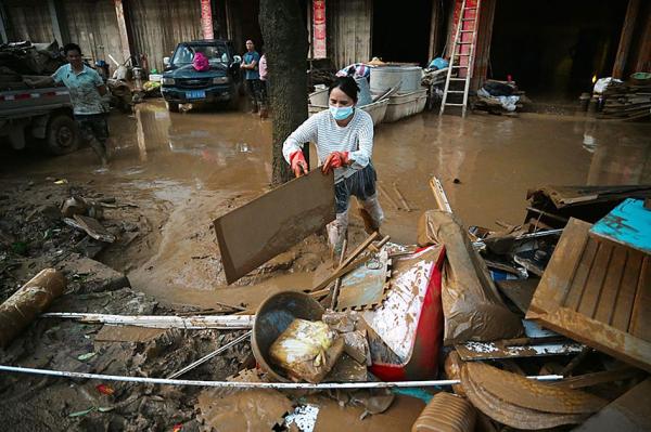 7月9日, 广西省甘塘市一名妇女正在清理洪灾后的房屋。(GREG BAKER / AFP via Getty Images)