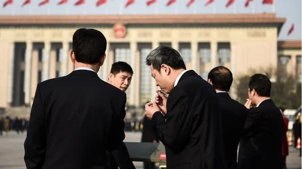 2018年3月19日，在北京人民大会堂举行的第十三届全国人民代表大会第七次全体会议召开前，与会代表们在天安门广场吸烟。（图片来源：Etienne Oliveau/Getty Images）