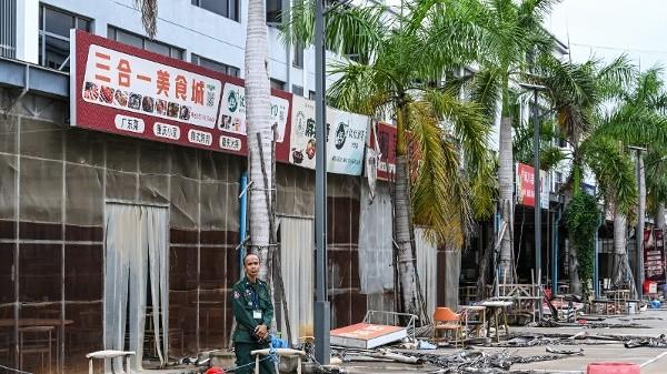 2026年9月22日，一名柬埔寨警官站在柬埔寨干丹省一家已被关闭的网络诈骗中心园区建筑外。该建筑有写着中文标牌“云尚酒店”。（图片来源：TANG CHHIN SOTHY/AFP via Getty Images）